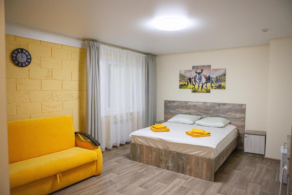 a bedroom with a bed and a yellow chair at Наша Арена in Yoshkar-Ola