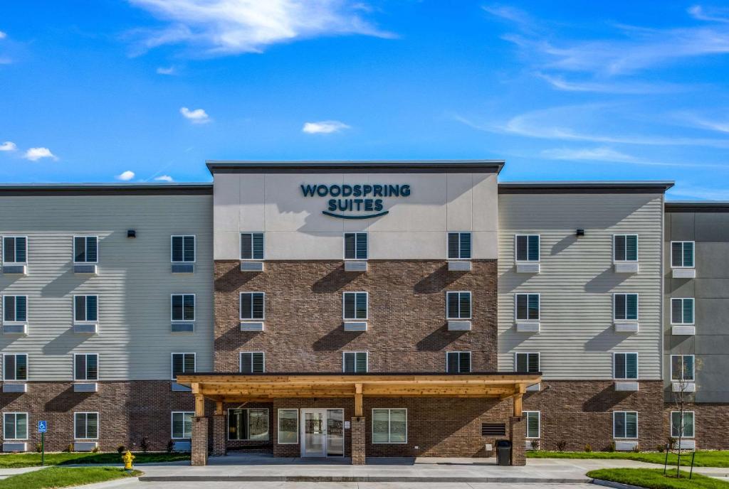 una representación de la parte delantera de un edificio con un cartel de la suite arbolada en WoodSpring Suites West Des Moines, en West Des Moines