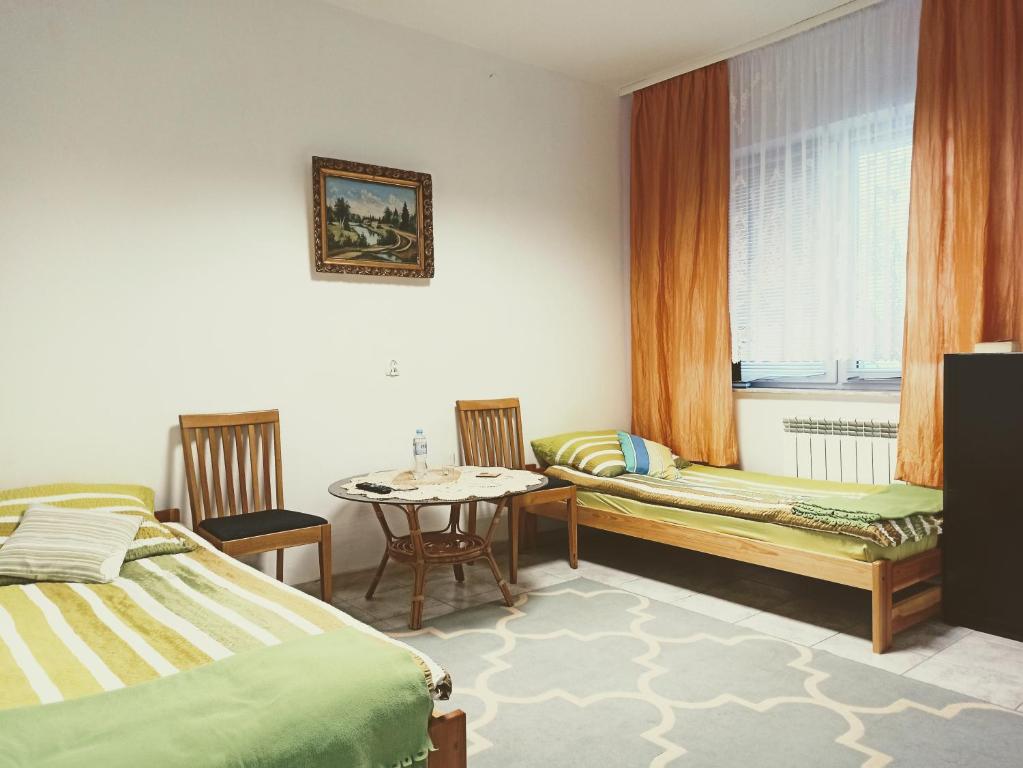 een kamer met 2 bedden, een tafel en een raam bij Kwatery w Gołdapi in Gołdap