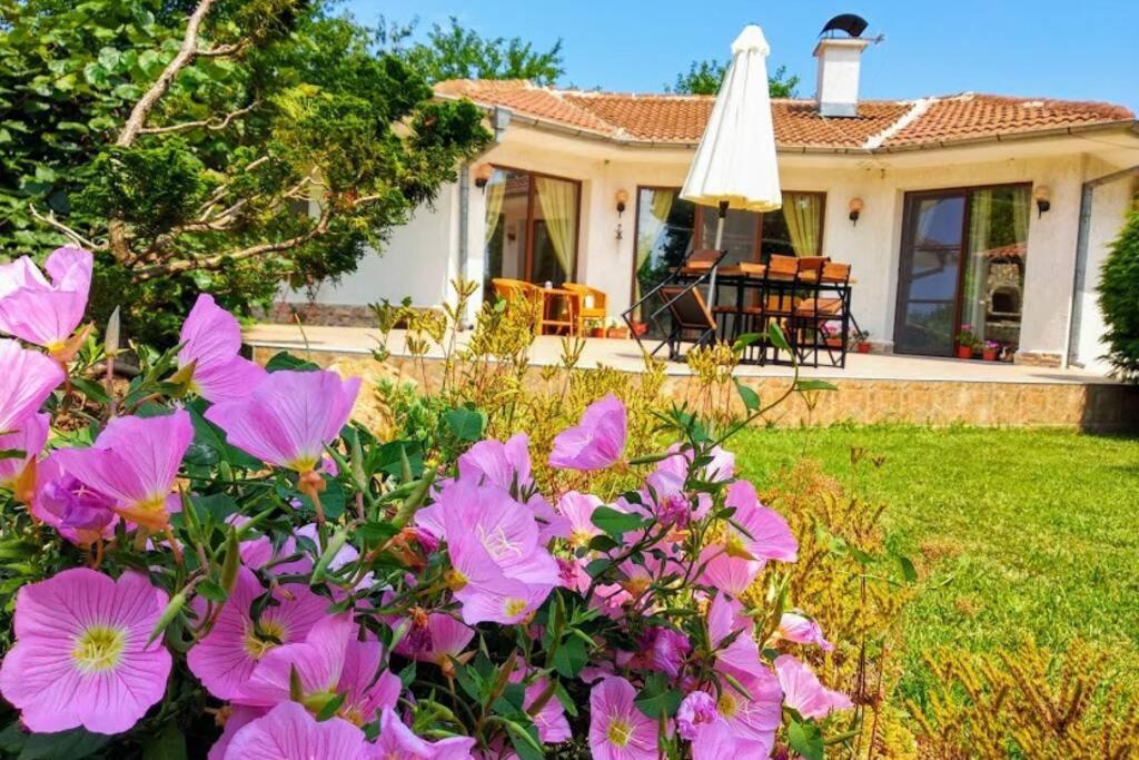 une maison avec des fleurs roses dans la cour dans l'établissement Guesthouse Oasis-Shabla, à Shabla