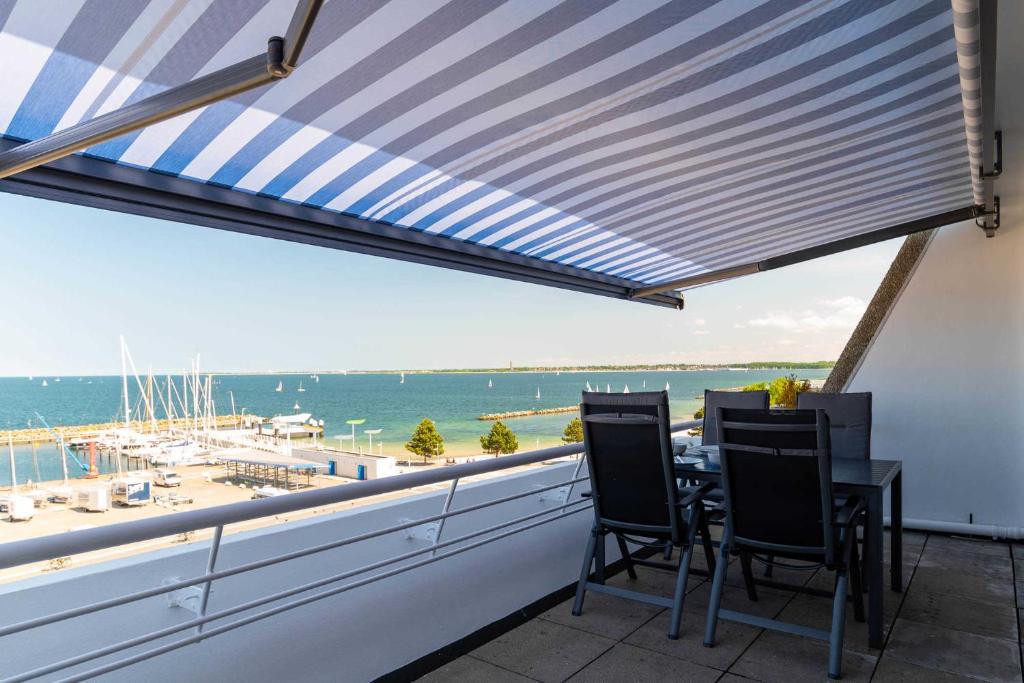 Un patio con mesa y sillas y vista al mar. en Ferienwohnung Pier 1167, en Schilksee