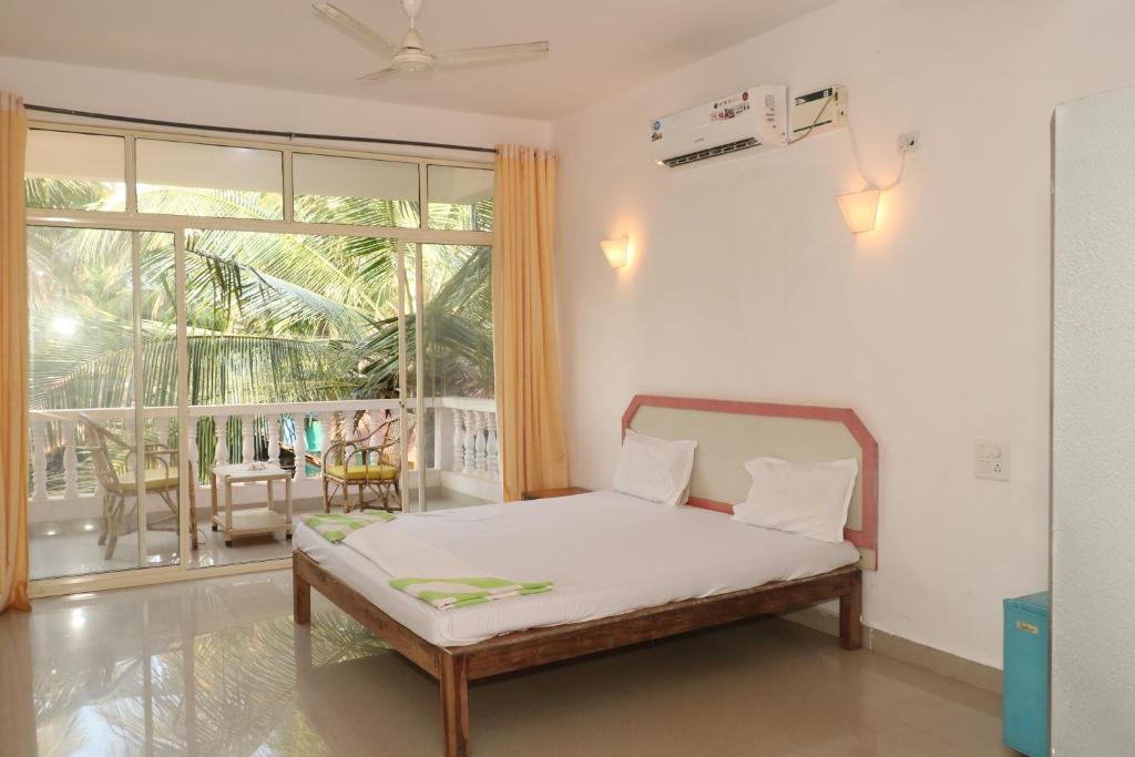 a bedroom with a bed and a large window at Lamarine Morjim Beach cottages in Old Goa