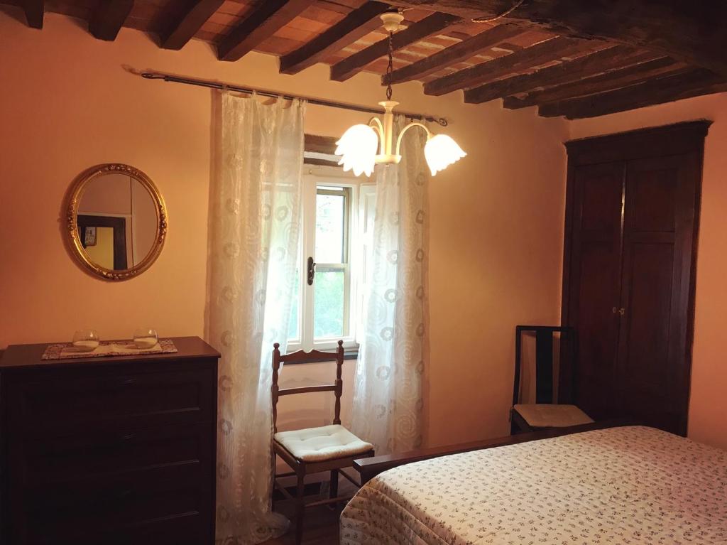una camera con letto, specchio e finestra di Casa Melograno a SantʼAndrea di Compito