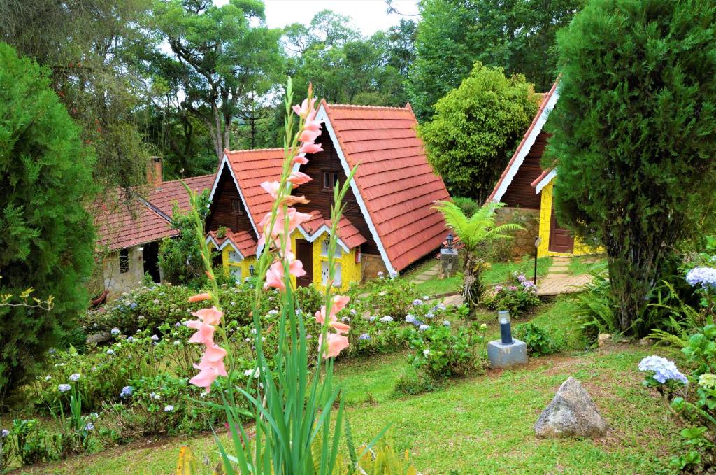 ein Haus mit rotem Dach im Garten in der Unterkunft Pousada Perola da Mantiqueira in Monte Verde