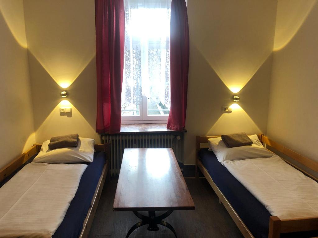 two beds in a room with a window and a table at Hotel Pension Schmellergarten in Munich