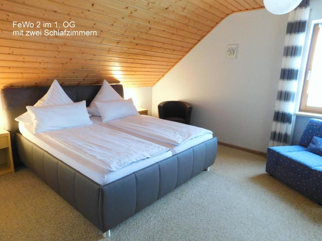 1 dormitorio con 1 cama grande y 1 silla azul en Ferienwohnung "Am Muschwitztal" Bad Steben / Carlsgrun, en Bad Steben
