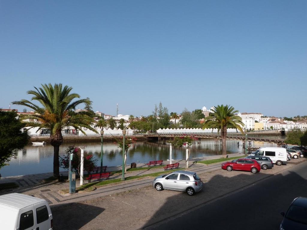 a group of cars parked in a parking lot next to a river at Rio Gilao in Tavira