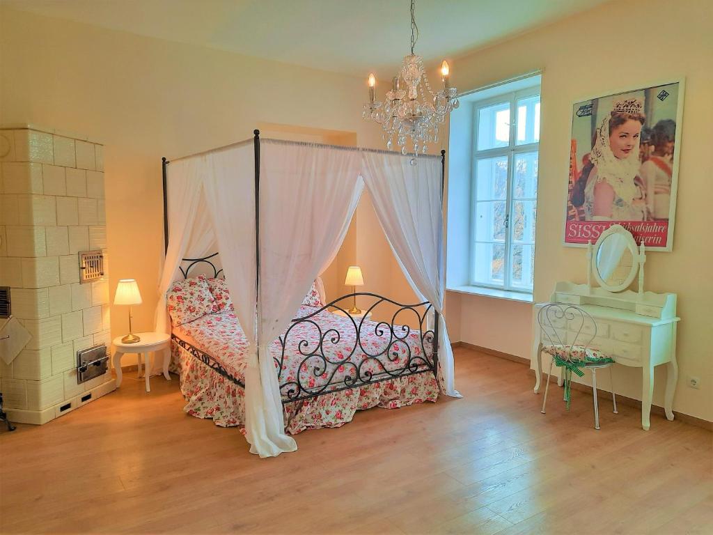 1 dormitorio con cama con dosel, mesa y ventana en Sisi-Schloss Rudolfsvilla - Appartement Elisabeth, en Reichenau