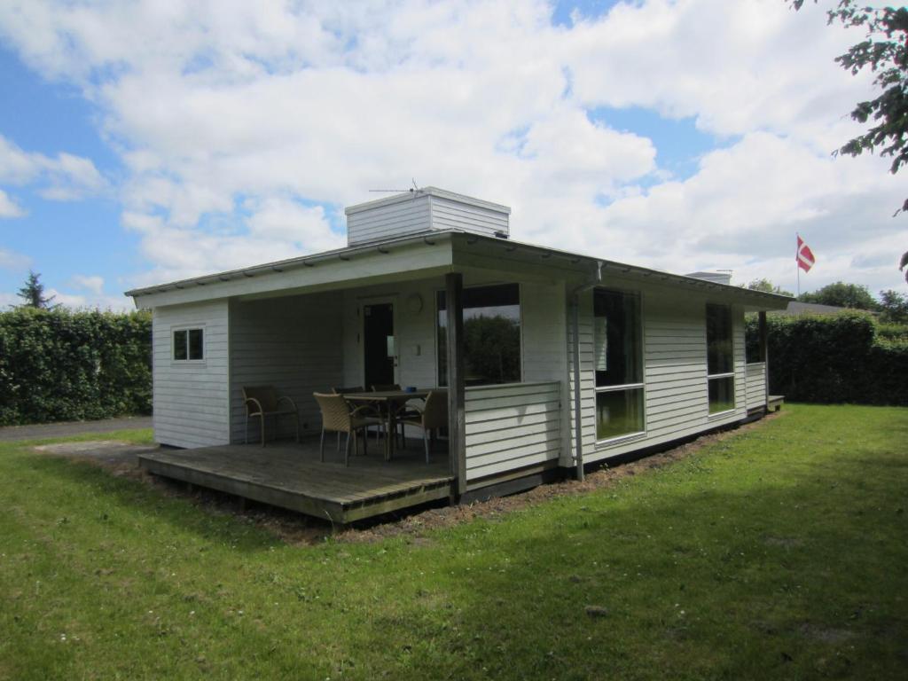 une petite maison blanche avec une table sur une pelouse dans l'établissement Hummingen Camping hus 2, à Dannemare