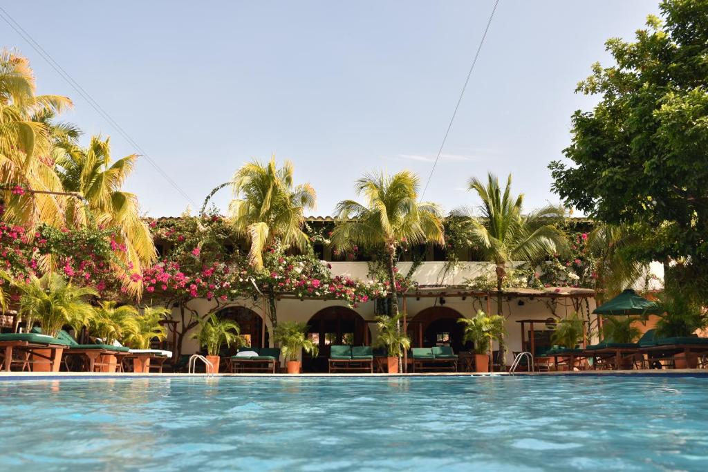 una piscina en un complejo con palmeras y un edificio en Hotel Mariscal Robledo en Santa Fe de Antioquia