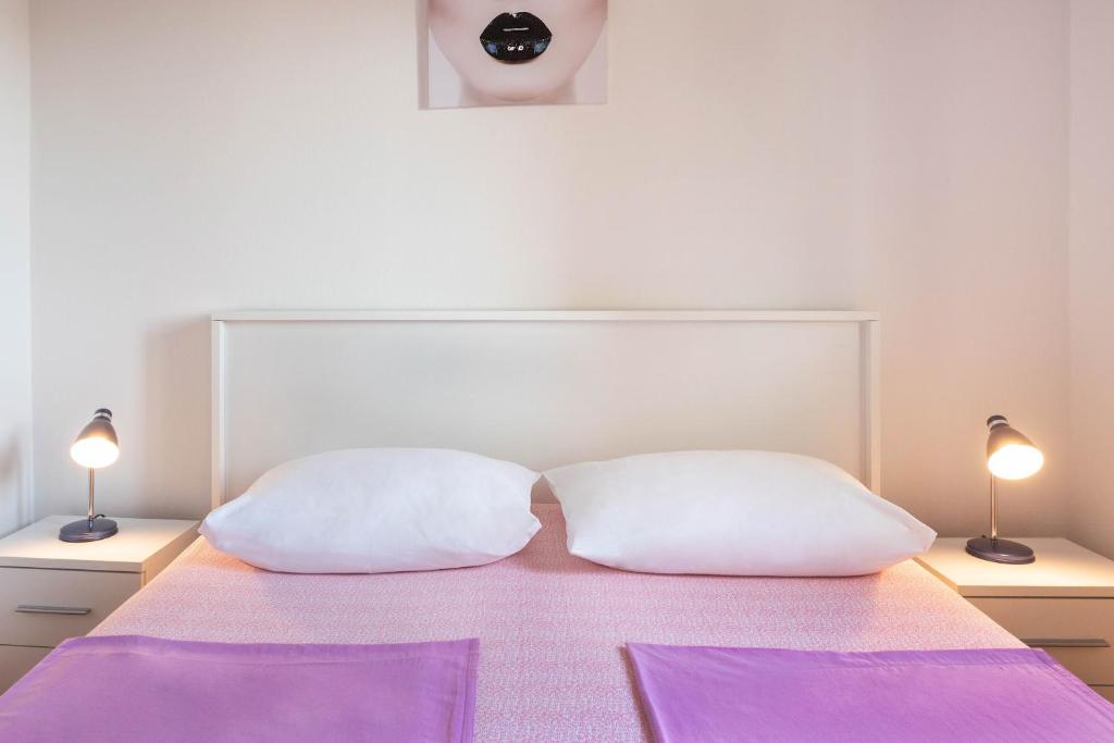zwei weiße Kissen auf einem Bett mit zwei Lampen in der Unterkunft Apartment Marin in Jadrija