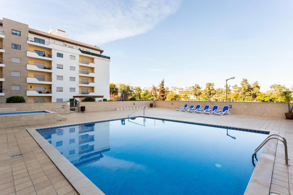 uma piscina com cadeiras e um edifício em James's Quinta das Palmeiras, spacious 2 bedroom apartment in luxury complex, walking distance to town and beach em Lagos