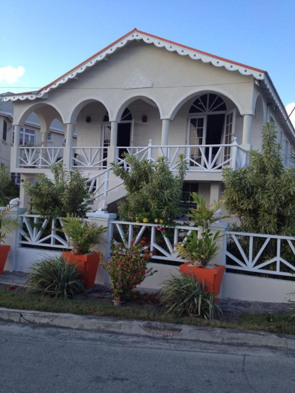 Biały dom z roślinami przed nim w obiekcie Sea Shells Villa w mieście Christ Church