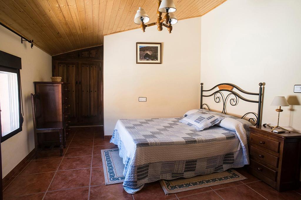 a bedroom with a bed and a wooden ceiling at Casa Rural El Chorritero in Ovejuela