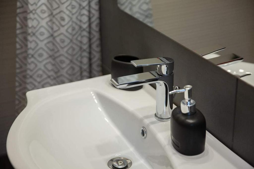 umywalkę w łazience z czarnym dozownikiem mydła w obiekcie Etoile apartment w mieście Perissa
