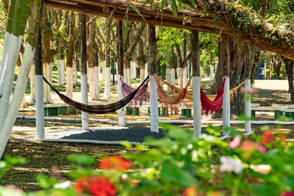 a hammock in a park with trees and flowers at VILLA DO SOSSEGO pousada in Lindóia