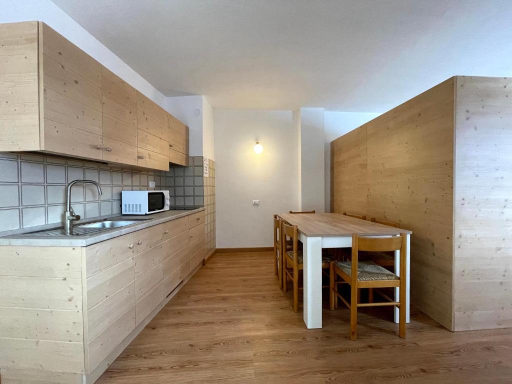 a kitchen with a sink and a table in a room at Casa Mammolo Falcade in Falcade