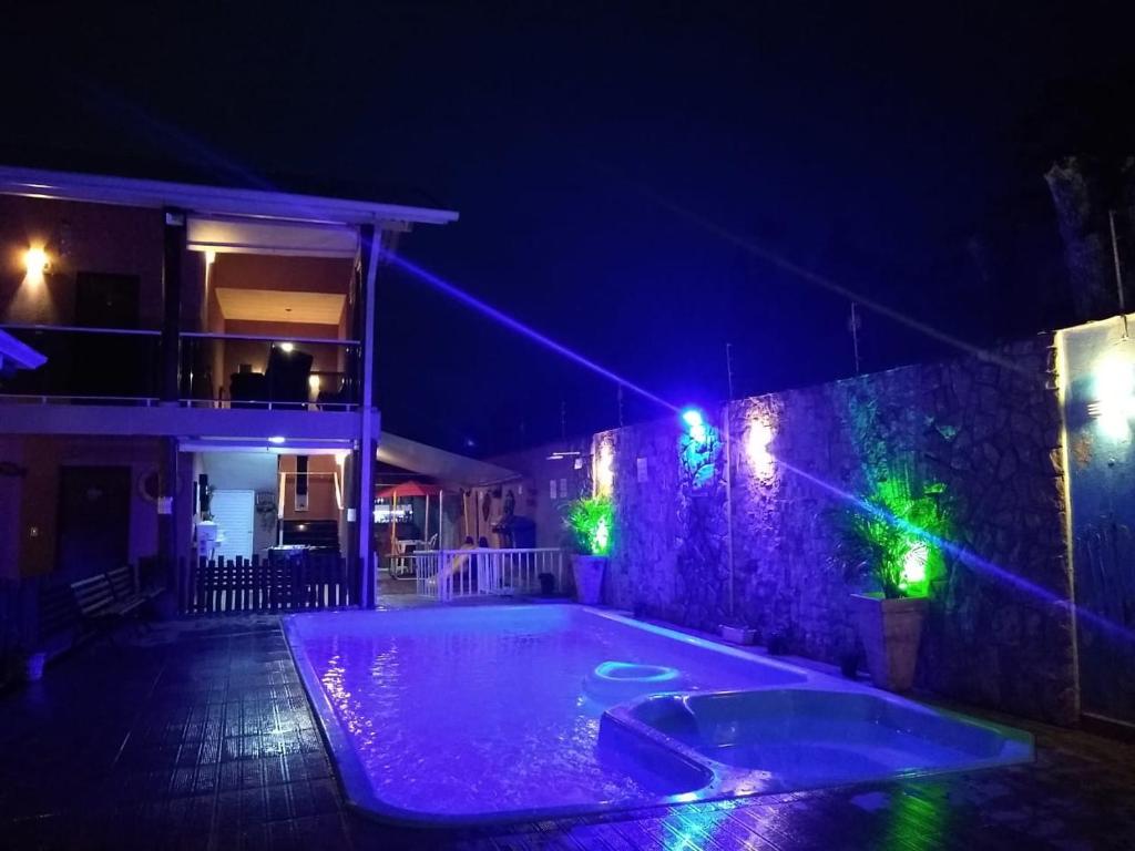 a swimming pool at night with lights on a wall at Pousada Parapuã in Caraguatatuba