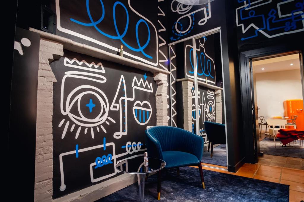 een kamer met een blauwe stoel en een muur met graffiti bij room five - parking, balnéothérapie, place nationale, un havre de paix in Montauban