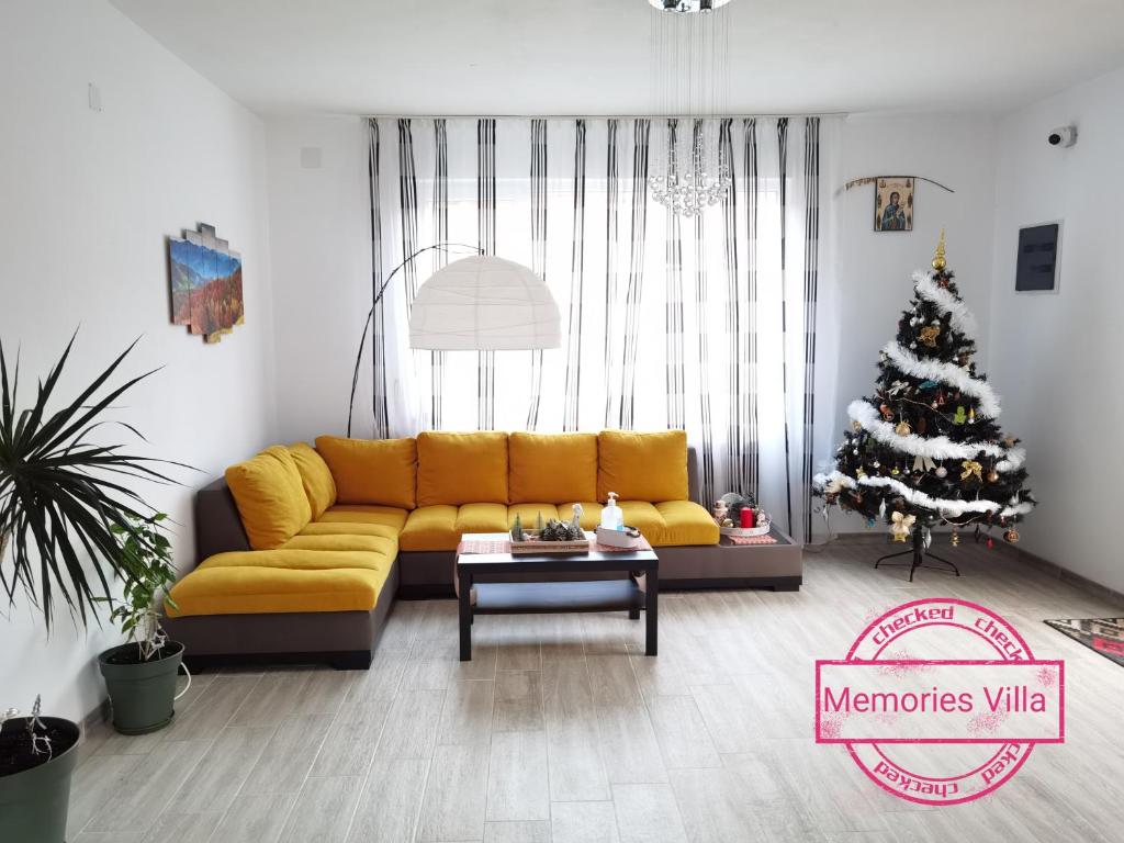 uma sala de estar com um sofá amarelo e uma árvore de Natal em Memories Villa em Moieciu de Sus