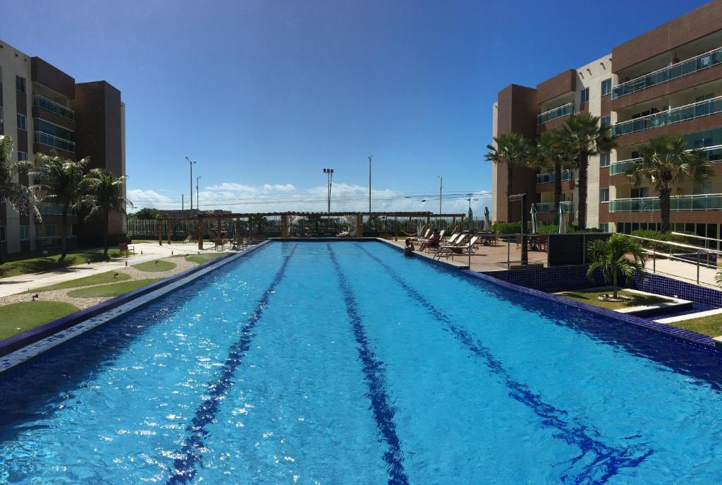 uma grande piscina com água azul em frente aos edifícios em Apartments Vg Fun Praia do Futuro em Fortaleza