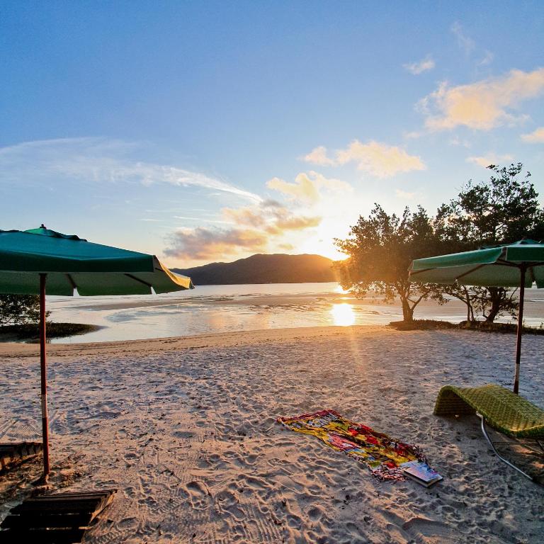 a beach with umbrellas and a towel on the sand at OPY CAMBOA in Governador Celso Ramos