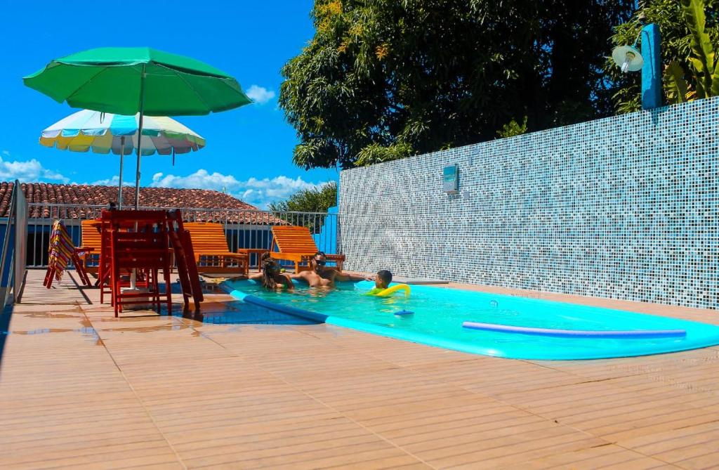 two children playing in a swimming pool with an umbrella at Pousada Beija-flor in Salinas da Margarida