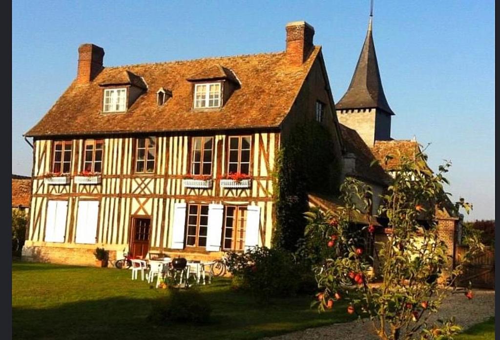 a large house with a church in a yard at Le petit Chapitre 