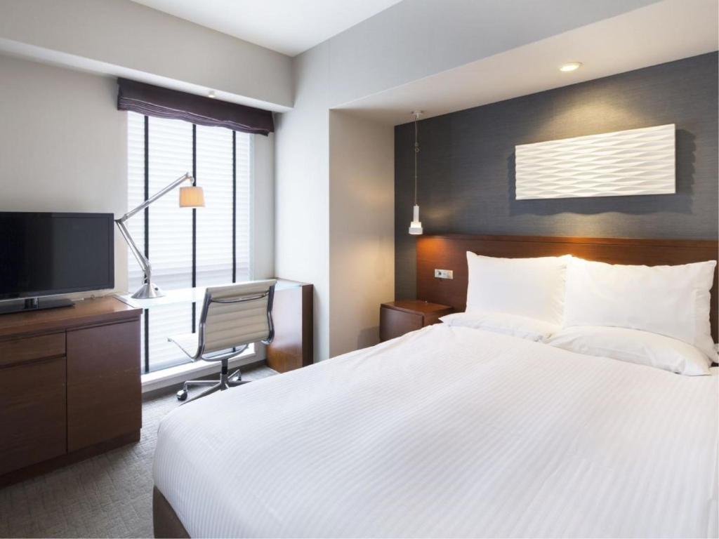 Habitación de hotel con cama y TV en HOTEL MYSTAYS Oita en Oita