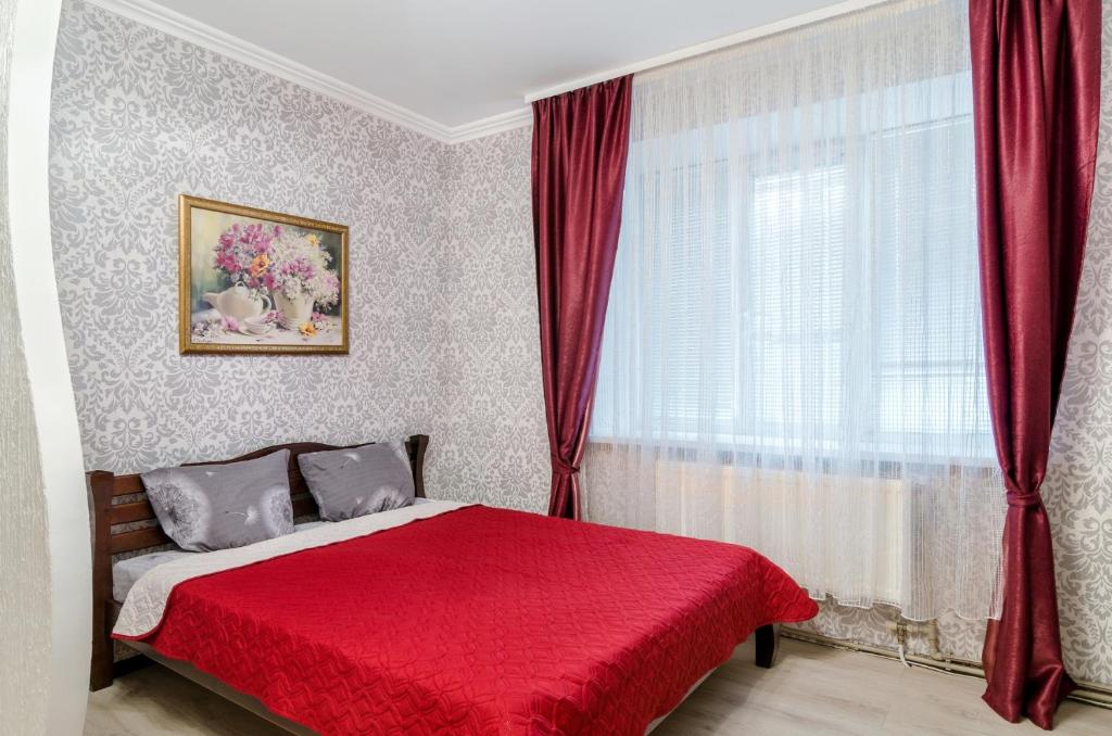 1 dormitorio con cama roja y ventana en Good Home en Sumy