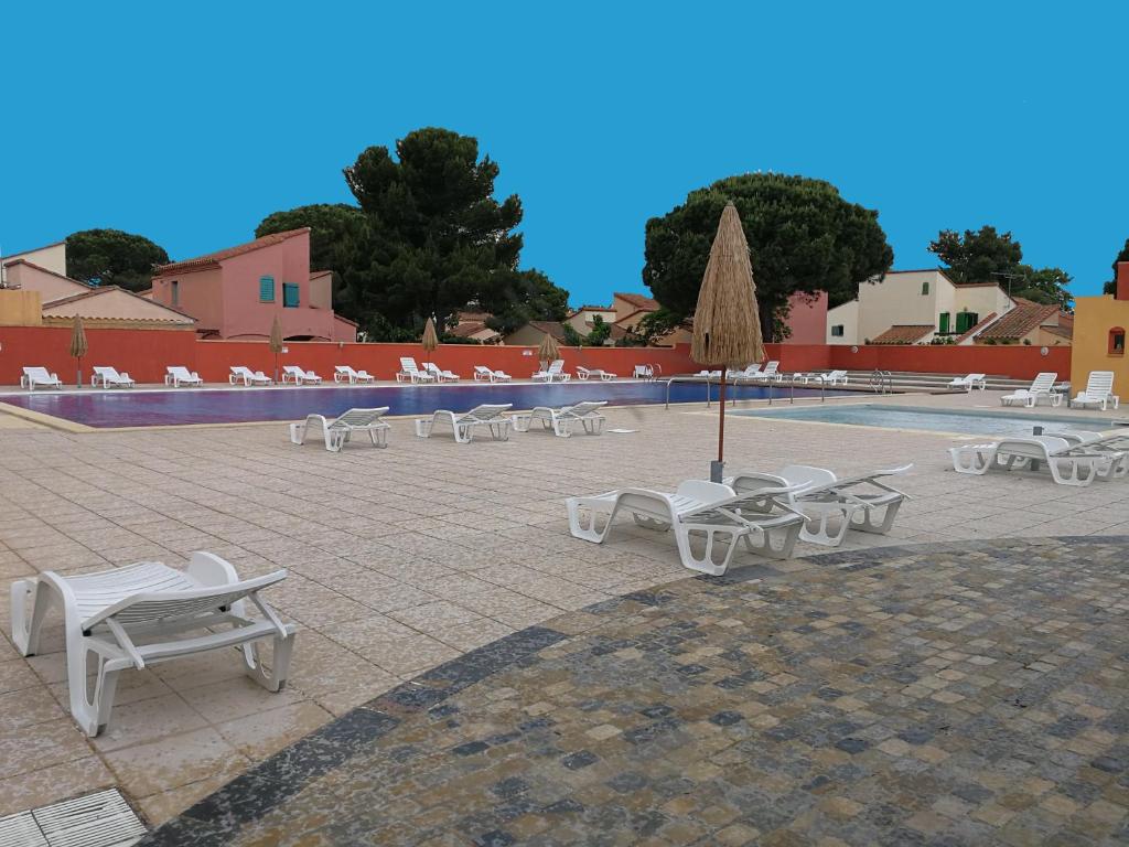 un grupo de sillas blancas y una piscina en Vacargeles casa Les Mûriers et Les Chênes verts calme clim wifi animations piscine mini golf en Argelès-sur-Mer