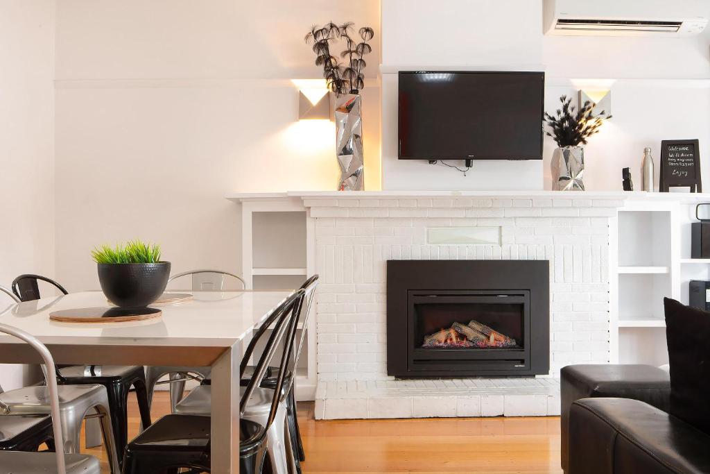 a living room with a fireplace and a table with chairs at 2easy on Hargreaves in Bendigo