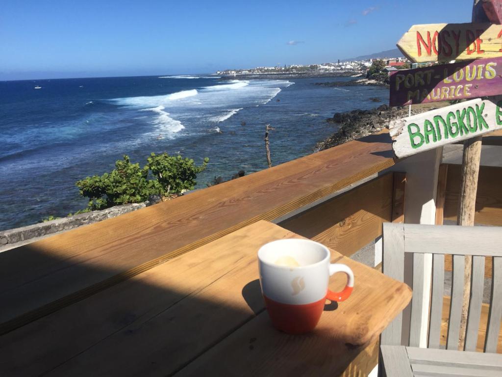 a coffee cup sitting on a wooden table overlooking the ocean at Le Cannelle in Saint-Pierre