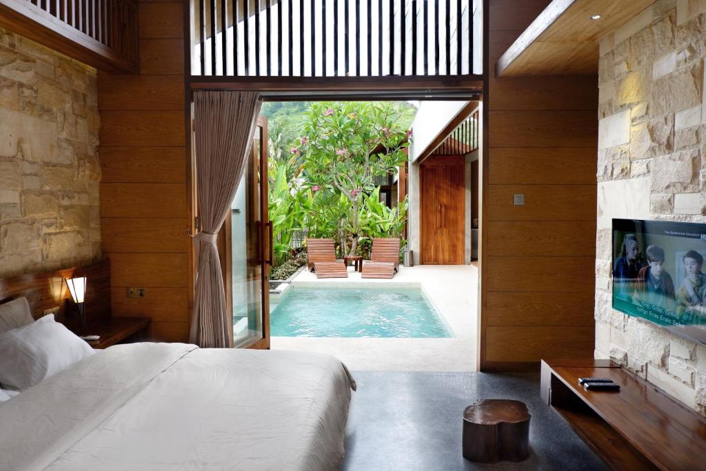 a bedroom with a bed and a swimming pool at Batatu Villas in Kuta Lombok