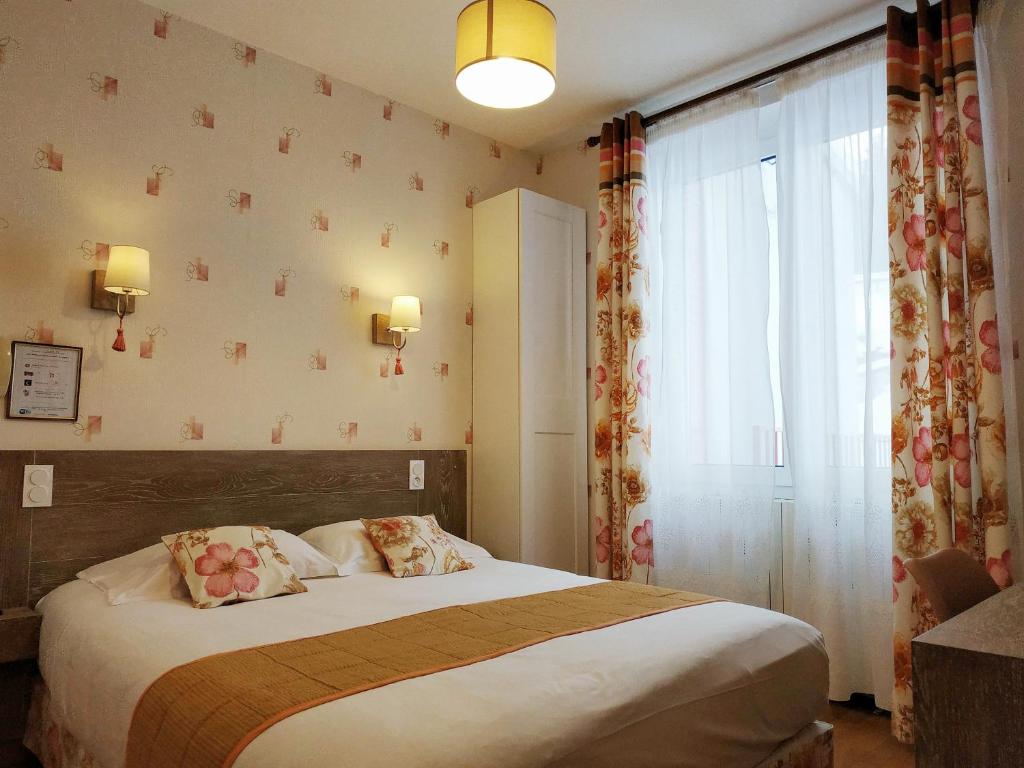 a bedroom with a bed and a large window at Hôtel Restaurant Le Grillon in Chambon-sur-Lac