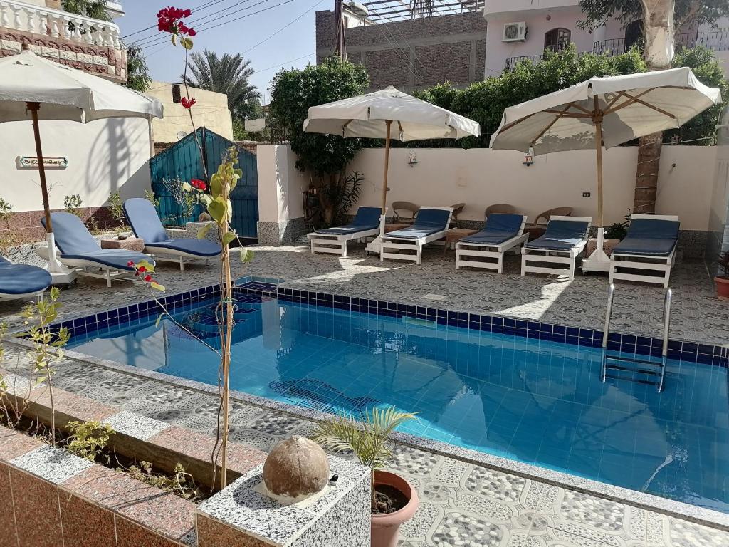 a swimming pool with lounge chairs and umbrellas at Luxor palace Apartments in Luxor