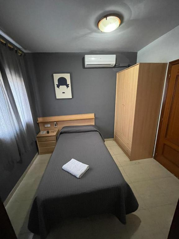 a small bedroom with a bed and a cabinet at Hostal del Carmen in Terrassa