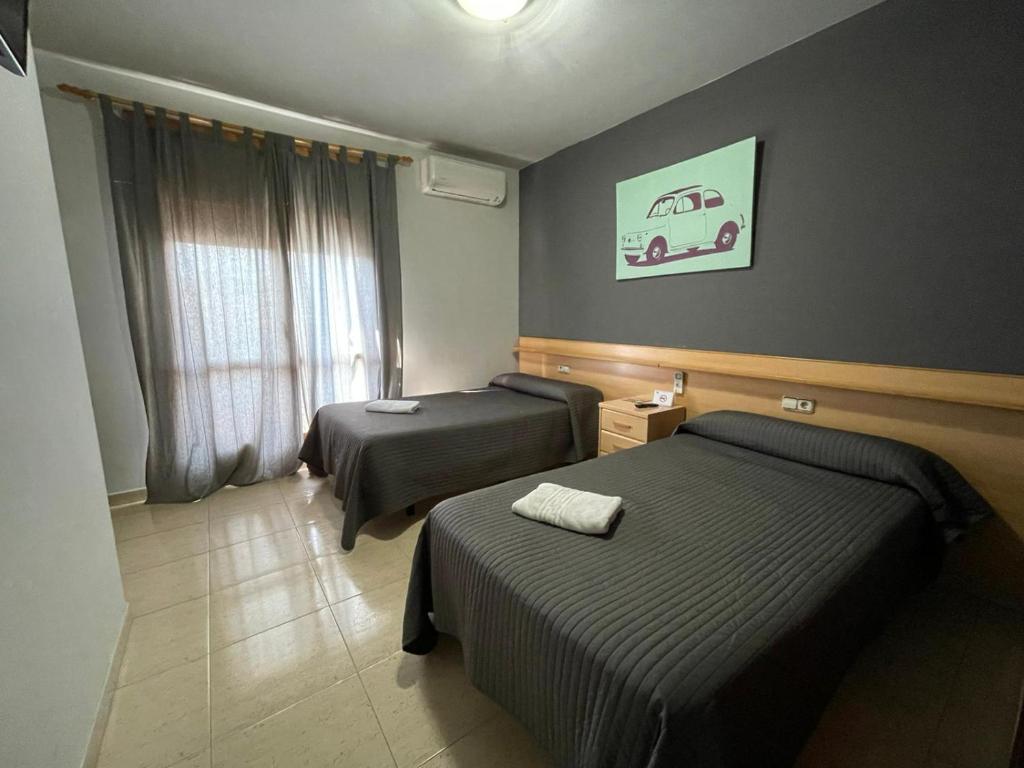 Habitación de hotel con 2 camas y ventana en Hostal del Carmen, en Terrassa