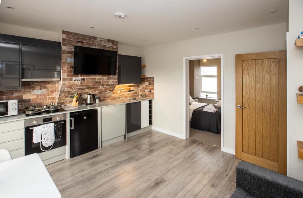 a kitchen with black appliances and a living room at Bright and Luxurious Flat in the Heart of Reading in Reading