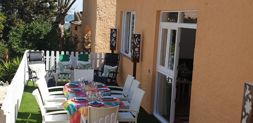 een tafel met witte stoelen en borden erop bij Casa con jardín a 40 metros de la playa. VR. in Palamós