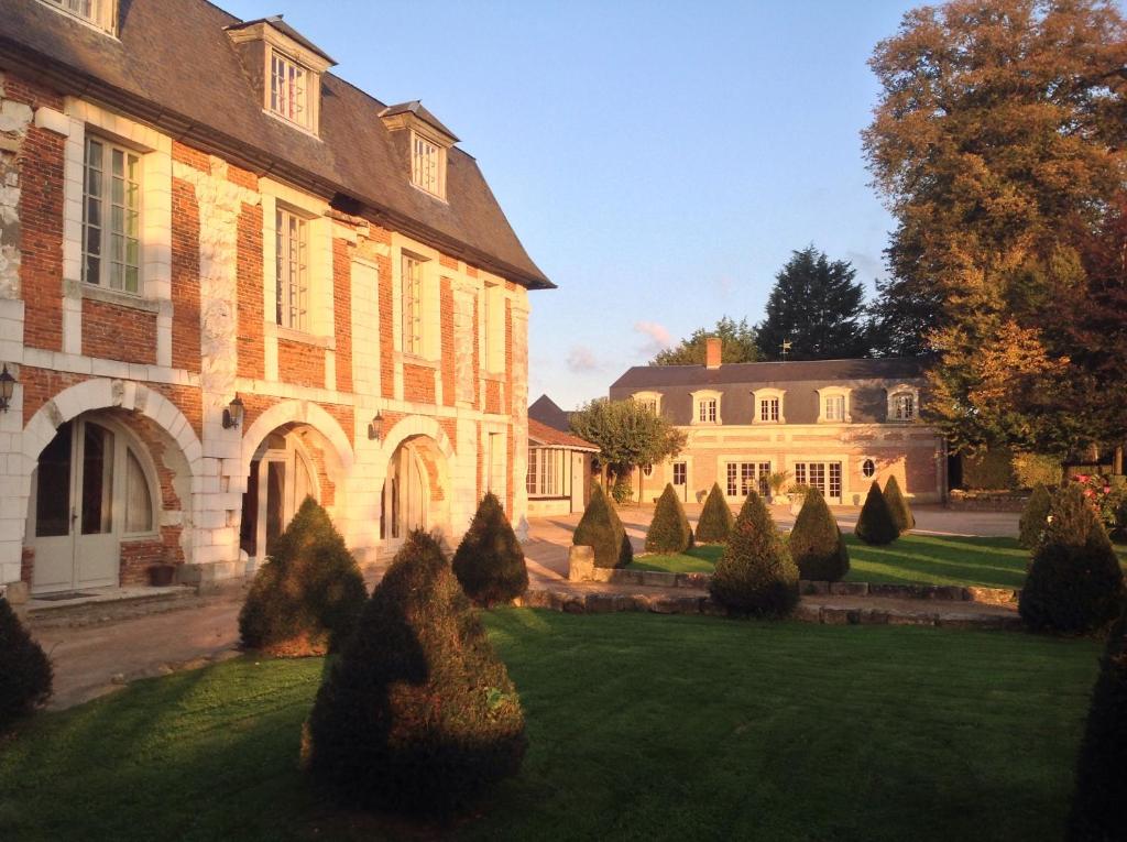 a large brick building with trees in the yard at L’orangerie chambres d’hôtes in Motteville