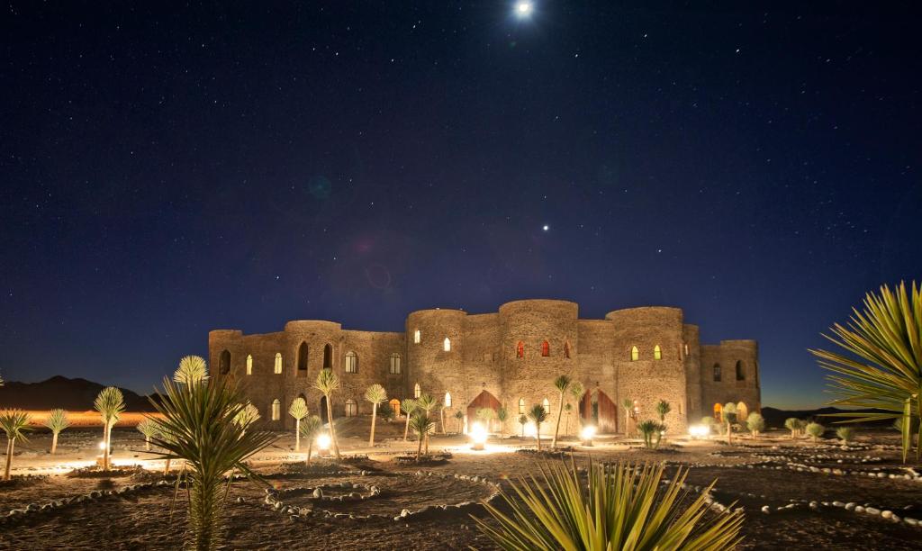 duży kamienny budynek w nocy z księżycem na niebie w obiekcie Le Mirage Resort & Spa w mieście Sesriem
