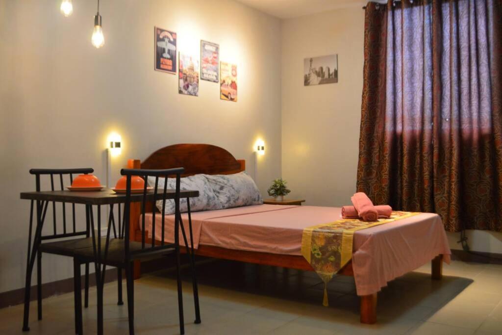 a bedroom with a bed with a table and a table with a chair at Dencio's Crib in Mactan
