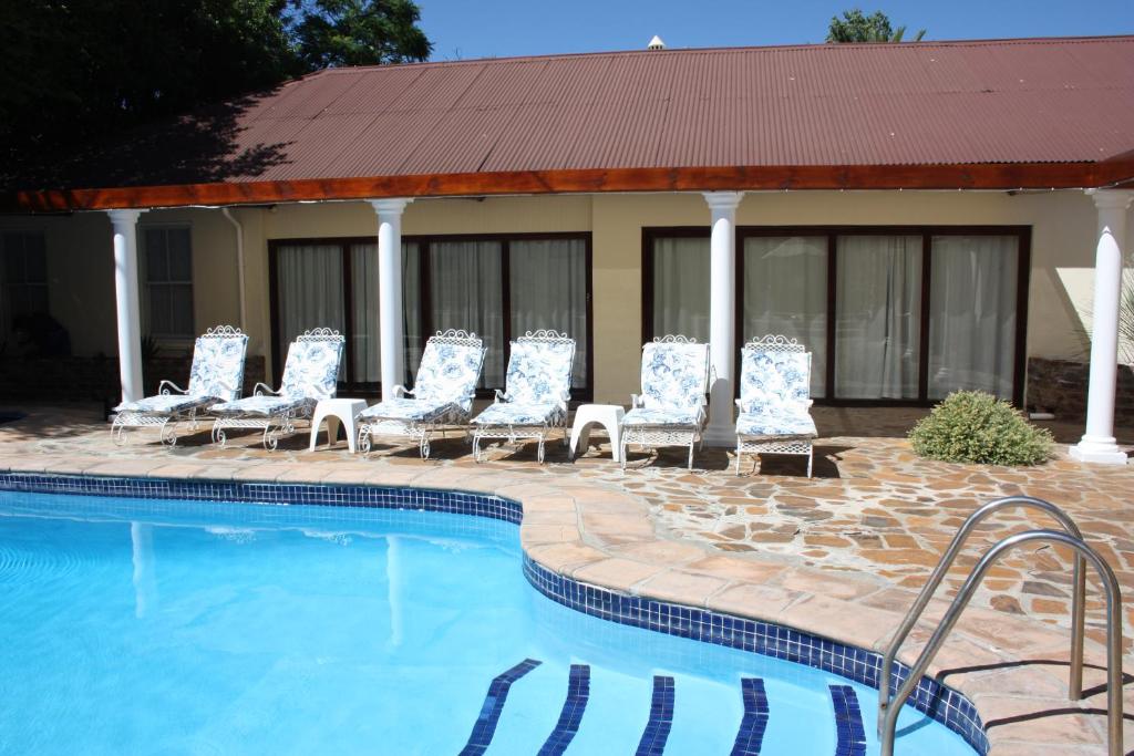 a group of chairs sitting next to a swimming pool at Karoopark Guest House in Graaff-Reinet