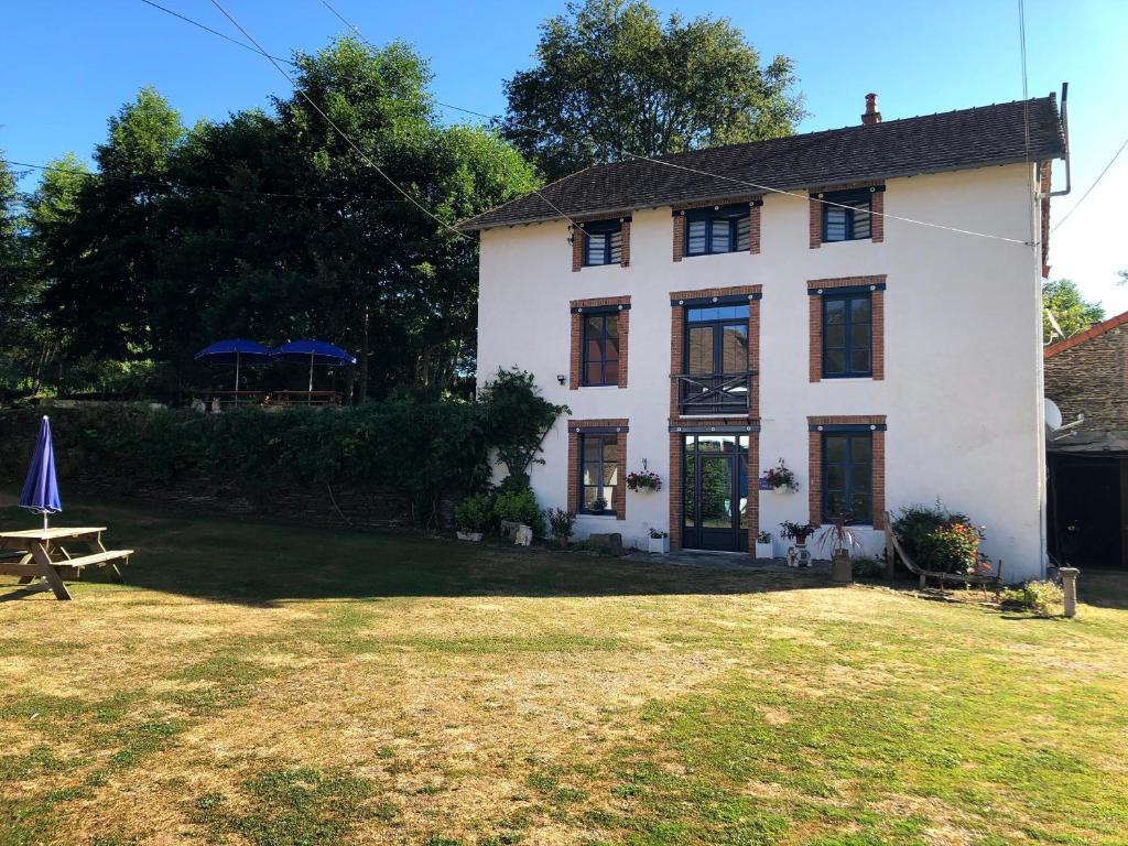 a white house with a picnic table in front of it at Moulin des Forges in Moutier-Malcard