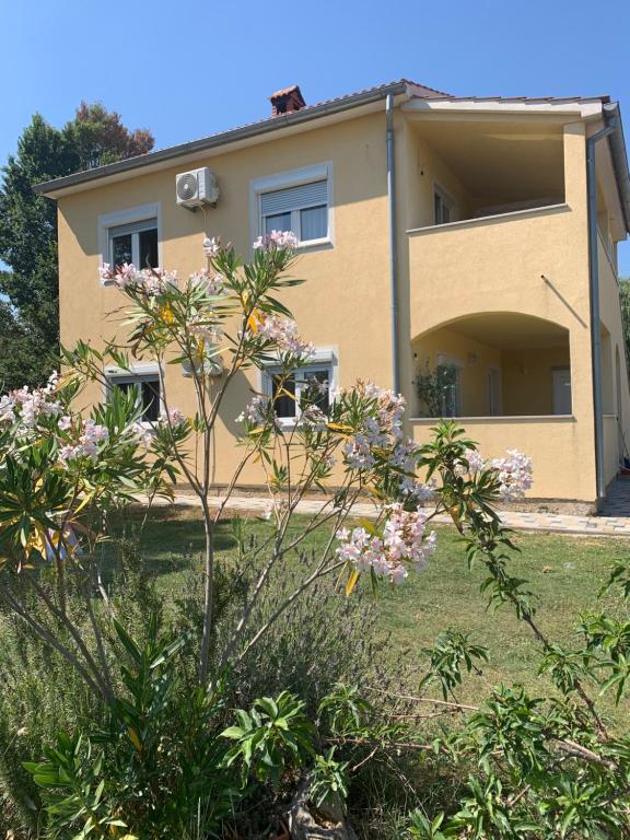a yellow house with flowers in front of it at Apartment CReO Loborika in Marčana