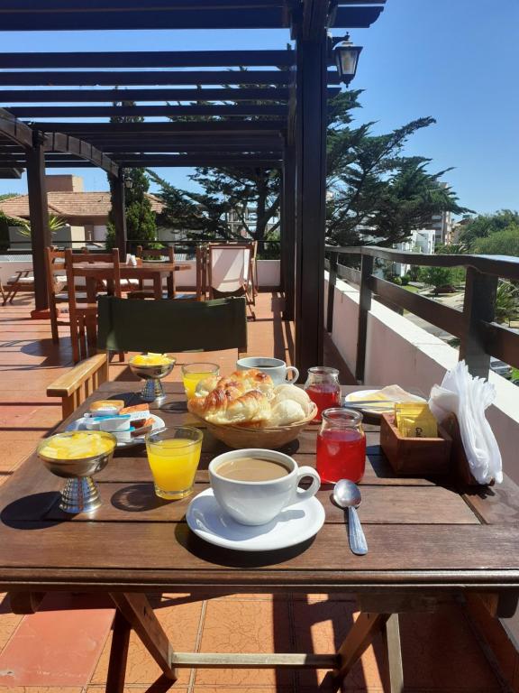 Una mesa de madera con comida y bebidas encima. en Hostería Santa Bárbara, en Villa Gesell