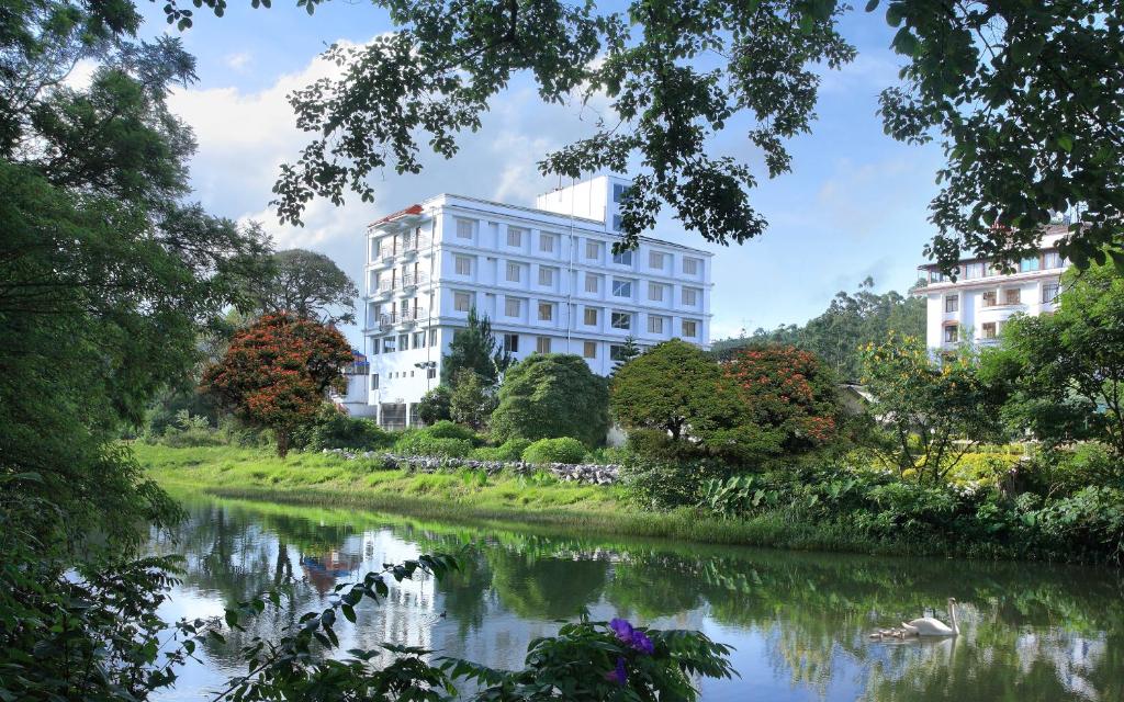 蒙納的住宿－大廣場酒店，一条树木繁茂的河旁的白色建筑