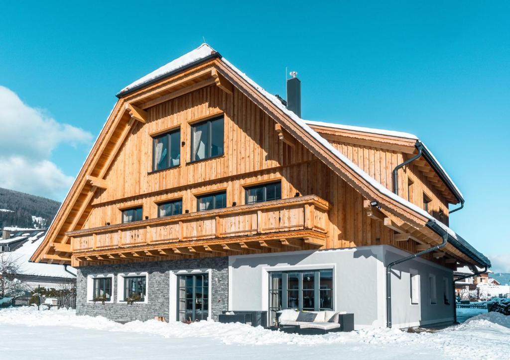 a house with a wooden roof in the snow at Schitter-Appartements in Mauterndorf