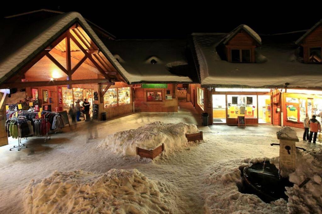 un magasin recouvert de neige la nuit avec des personnes debout à l'extérieur dans l'établissement RDC La joue du loup, à Saint-Étienne-en-Dévoluy